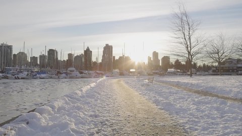 Seawall in Stanley Park, Boats in Marina, Coal Harbour, Urban City Skyline and Ice on water during Holiday Winter Season. Downtown Vancouver, British Columbia, Canada