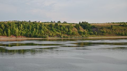 Riverbanks of the Volga river go by in a slow pano, seen from a river cruise ship navigating in summer