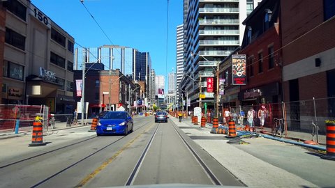 Toronto, Ontario, Canada - August 5th, 2019. Driver Point of View Driving Through Construction Zone Downtown City During Day. Drive Car Vehicle Along Street Tall Buildings and Pedestrians