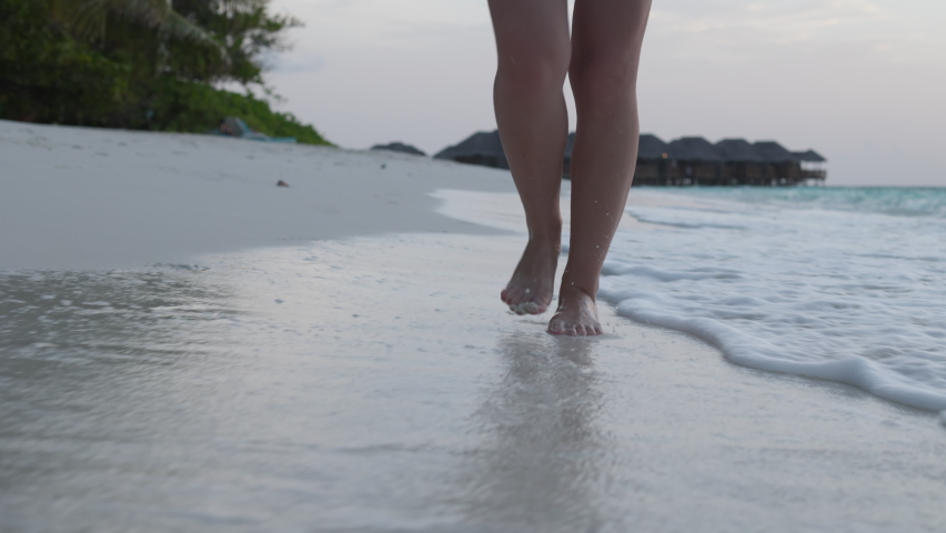 Slow motion of woman feet walking barefoot on the white sand beach at sunset. Female tourist on summer vacation in Maldives. | Shutterstock HD Video #1085640653