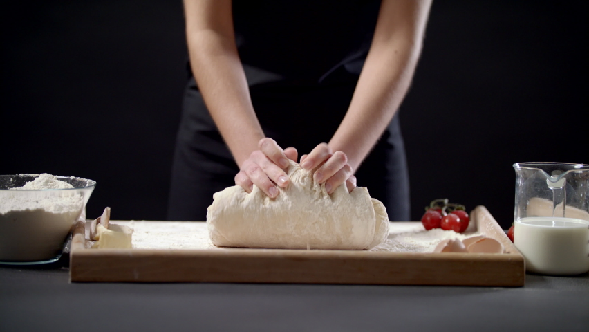 Closeup Shot Of Female Hands Of Baker Kneading Dough In Flour On Wooden Board On Table In Bakery Shop, Woman Making Bread Using Traditional Recipe At Home On A Black Background Slow Motion | Shutterstock HD Video #1085641475
