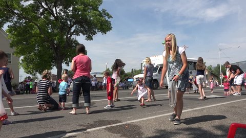 MORONI, UTAH - JUL 2015: Parade rural boys dangerous on top of bus throw candy 4K. Small central Utah rural community of Moroni celebrates the 4th of July. Family and friends gather along Main Street.