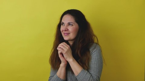 Beautiful woman on a yellow background shows the emotion of embarrassment.