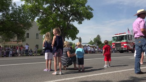 MORONI, UTAH - JUL 2015: Parade rural fire truck throws candy to children 4K. Small central Utah rural community of Moroni celebrates the 4th of July. Family and friends gather along Main Street.