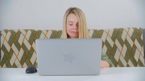 White blonde woman working freelance on computer on lockdown. Caucasian female doing distant work online with laptop. Freelancer writer person typing text on notebook pc in 4k stock video clip