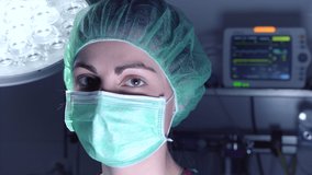 Adult woman in medical mask and hat looking and smiling at camera before performing surgery in hospital. High quality 4k footage