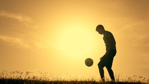 Boy with soccer ball. Child in park plays at sunset.Boy juggles soccer ball.Child dream of football match.Sports training in park. Sportsman is in control of ball. Child juggles ball.Healthy lifestyle