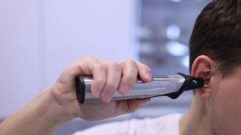 Close up Man using special trimmer to automatic cut hair in the ears