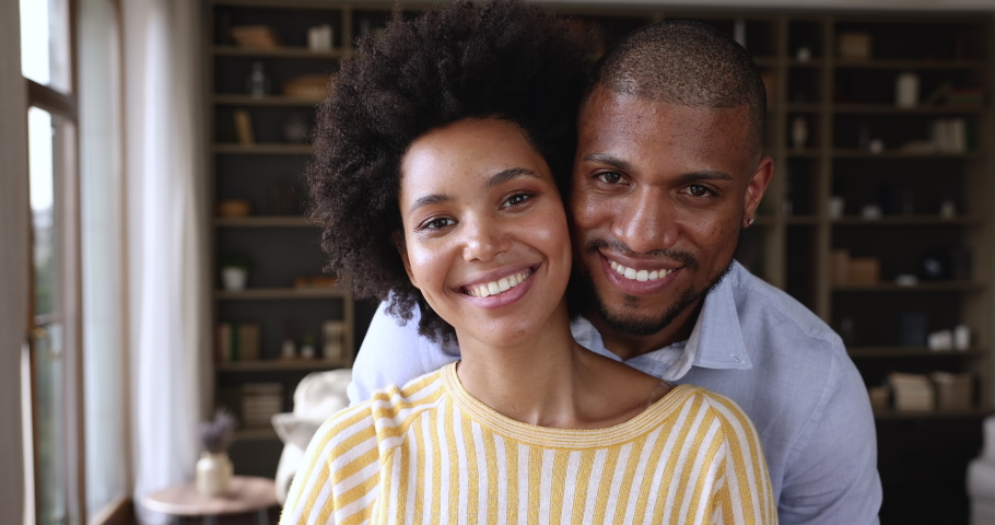 Headshot portrait happy millennial Black husband wife posing at home smiling looking at camera. Satisfied young married family couple get loan mortgage leave positive video feedback enjoy good service Royalty-Free Stock Footage #1085646230
