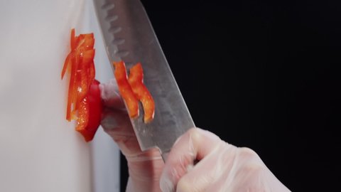 Chief knife cuts the red pepper for small slices. Slicing sweet pepper on white cutting board. Closeup cut the sweet pepper. Vertical video slow motion