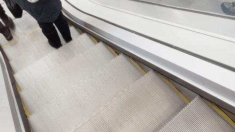 First person view of close up footage of moving empty modern escalator stairs, glass railings