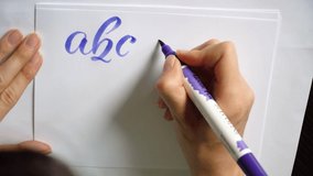 woman hand writes a calligraphic alphabet in this motion video 