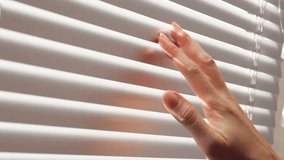 female hand separating slats of venetian blinds with a finger to see through - Powered by Shutterstock - Get 15% off with code: PIKWIZARD15