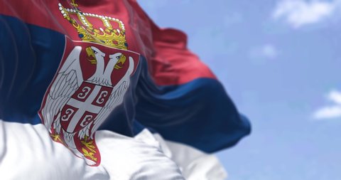 Detail of the national flag of Serbia waving in the wind on a clear day. Democracy and politics. European country. Selective focus. Seamless Slow motion