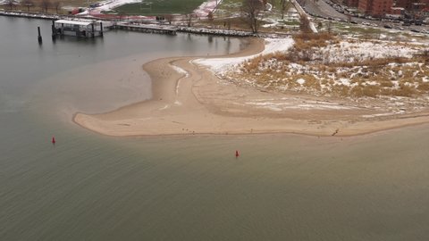 An aerial view of Coney Island Creek, NY on a winter morning. The drone camera truck right over the creek with apartment buildings and the beach in the background on a cloudy day.