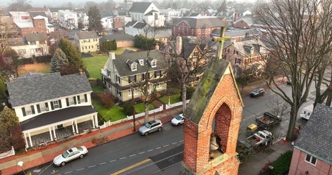 Aerial orbit of church belfry tower steeple in neighborhood in USA. Moody fog in morning light. Christian Catholicism religion in America.