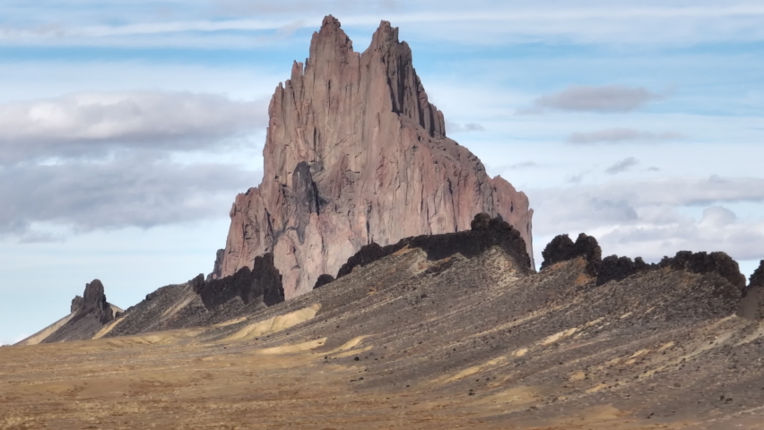 Cinematic cliff with clouds in blue sky on motion background with parallax effect. Southwest USA, New Mexico desert wanderlust travel. Nature wilderness park with epic Shiprock landscape shot on drone