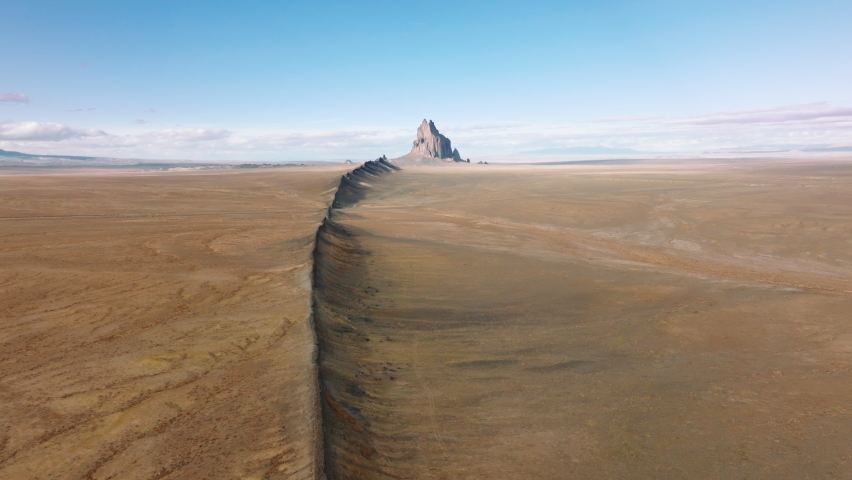 4K nature landscape with backbone hill in direction of Shiprock mountain visible remotely at the horizon line. Aerial Shiprock is dramatic geological wonder in deserted southwest of New Mexico, USA