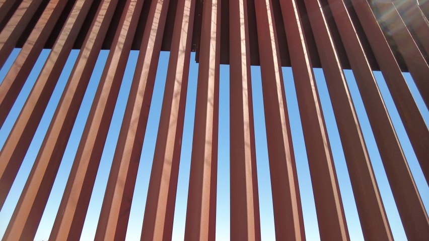 US-Mexico Border Fence with barbed wire on top, tilt-up shot. Royalty-Free Stock Footage #1085661182