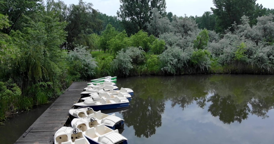 Rental Boats Mooring On A Wooden Dock In Calm Lake. Aerial, Tilt-down