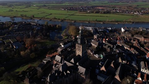 Aerial rotation reveal of Walburgiskerk church tower in the middle of picturesque tower town Zutphen in The Netherlands with river IJssel and floodplains in the background