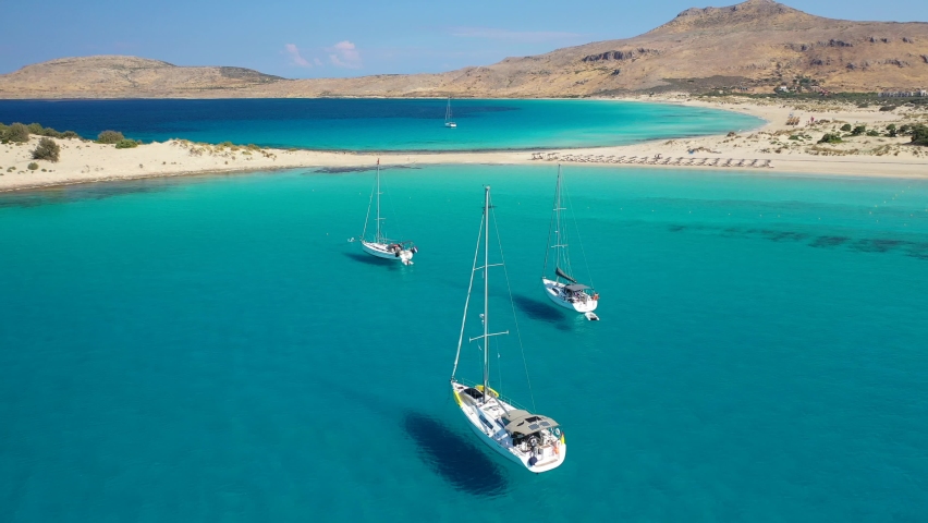 Aerial drone video of tropical paradise exotic island bay with emerald crystal clear beach visited by luxury yachts and sail boats in Caribbean destination