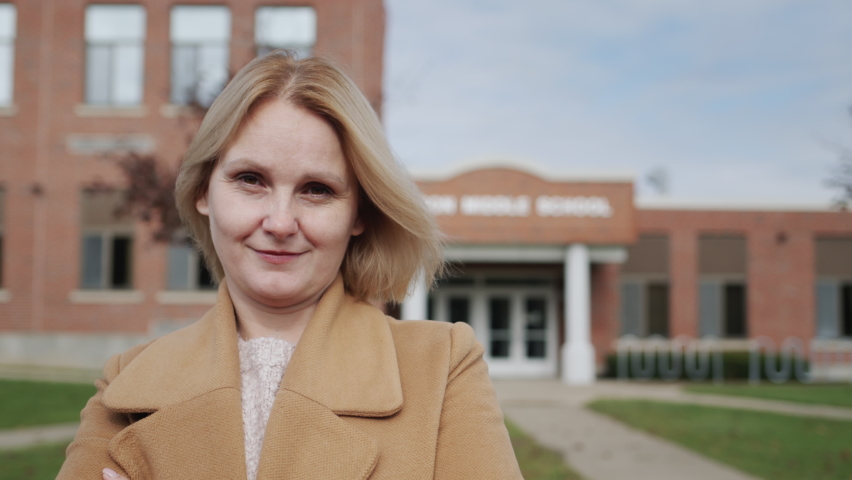 Portrait of a female teacher against the background of an elementary school building in the United States
