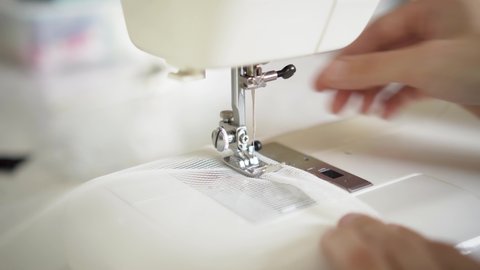 Man sews at a sewing machine. Designer sitting and sewing. Dressmaker working on the sewing machine. Concept of clothing production. Close up view of hands