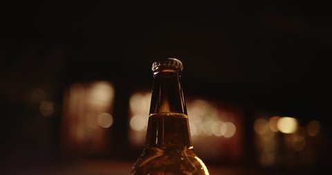 Men's hands open bottle of beer. Beer foam escapes from under the lid. Opening a brown beer bottle with an  opener. Celebrating concept. Abuse and alcoholism concept