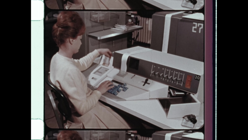 1960s Pasadena, CA. Female office worker processes data on retro computer. Woman types on Vintage Computer Console. 4K Overscan of Archival 16mm Film Print