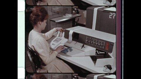 1960s Pasadena, CA. Female office worker processes data on retro computer. Woman types on Vintage Computer Console. 4K Overscan of Archival 16mm Film Print