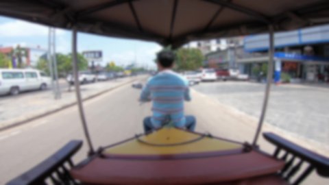Blurred defocused POV of a tourist in a tuk tuk in Siem Reap driving through its streets. A local taxi takes tourists through the streets of Cambodia a Southeast Asian city