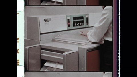 1970s New York, NY. Woman makes copies on photocopier. Vintage office interior as female office worker uses retro office equipment. 4K Overscan of Vintage Archival 16mm Film Print