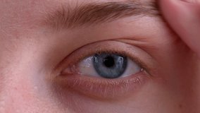 close shot video 4k eyes of a girl of blue color look directly into the camera and blink, eyes of a woman