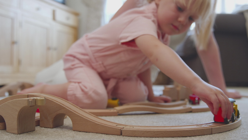 Close Up Of Mother And Daughter At Home Playing With Wooden Train Set Toy On Carpet