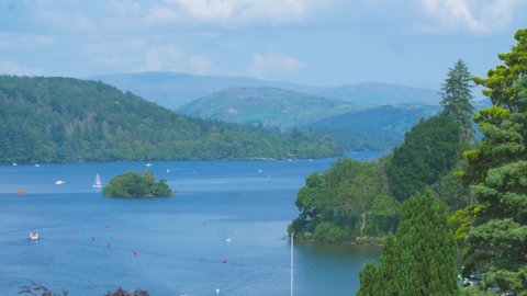 Scenic view of Lake Windermere in the Lake District, Cumbria on a gorgeous summers day. Beautiful blue sky, complemented by the glistening blue waters, surrounded by nature and tourism