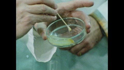 1980s: Lab. Man pours blob out of test tube. Men speak. Man pushes blob around petri dish. Colorful outlines of human body. Water runs over rock.