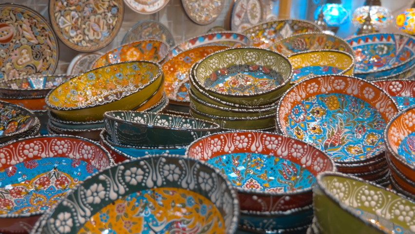 Rows of beautiful, ornamented be floral pattern, colorful ceramic plates on the market counter. Shot in motion. Closeup