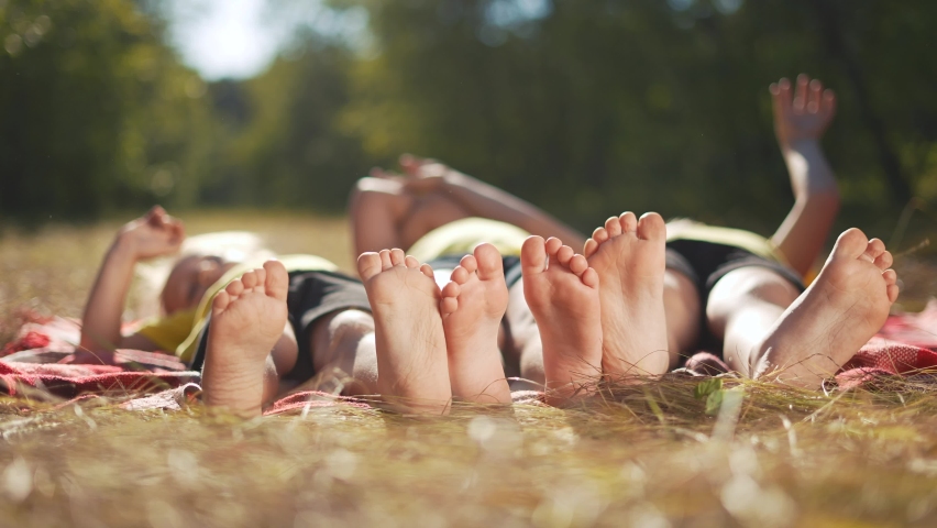 happy family. close-up of a kids leg feet lie on the grass in the summer park. children feet close-up team together happy childrens friendship. children lie in the park on sun the grass family Royalty-Free Stock Footage #1085691371