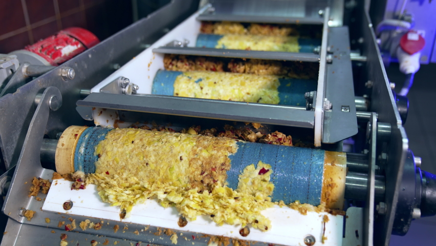 Rotating shafts transporting mashed apples pulp. Conveyor line at the factory producing organic apple juice fruit.