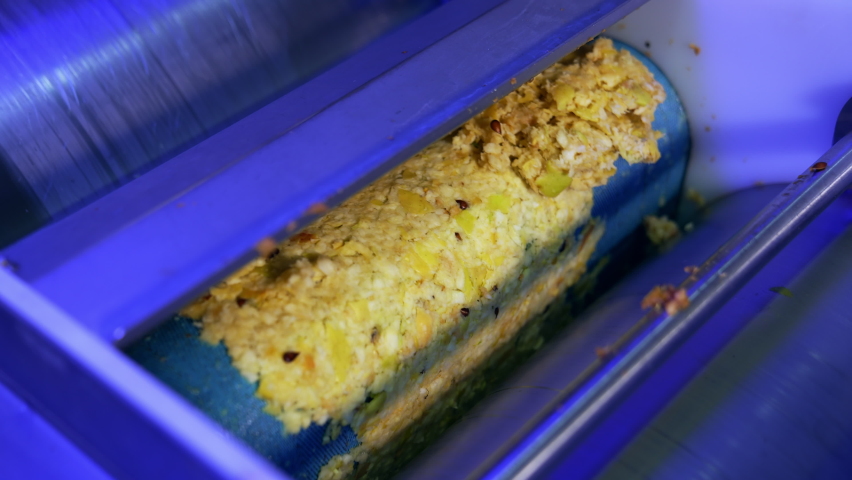 Few shafts covered with apple pulp rotating to squeeze juice. Close up. Organic apple juice production at the food factory.