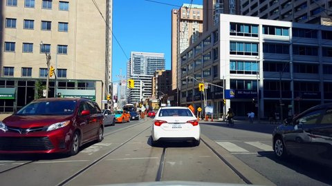 Toronto, Ontario, Canada - August 5th, 2019. Driver Point of View Waiting and Turning Left Driving Through Downtown City During Day. Drive Car Vehicle Along Street Tall Buildings and Pedestrians 