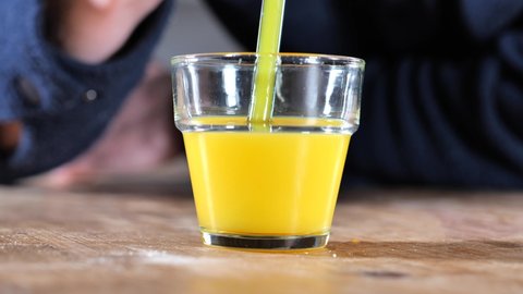 `Drinking orange juice from a glass through a straw