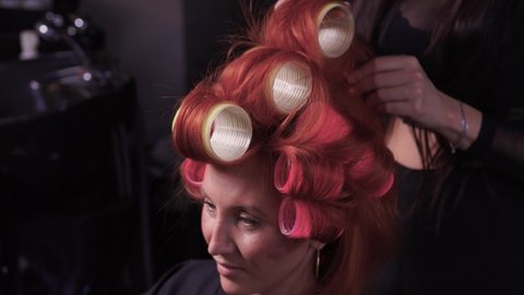 Closeup of red hair during hair dressing with curler.