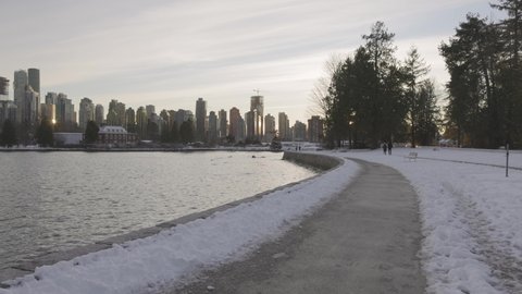 Downtown Vancouver, British Columbia, Canada - December 31, 2021: Coal Harbour, Urban City Skyline and Ice on water during Winter Season. Seawall in Stanley Park.