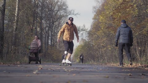 UFA RUSSIA - 10.11.2021: A young man with a metal bionic prosthetic leg is riding a skateboard in the autumn forest. An artificial leg pushes off the asphalt on a skateboard