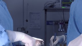Tilt up shot of Female surgeons in medical uniform using professional tools while standing under bright light in operating theater. High quality 4k footage