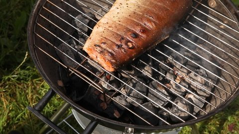 Fresh salmon fish on barbecue grill grate. Fish cooking on fried smoked grill. Chef cooking healthy lunch roast bbq on countryside campfire. Camping food, picnic, weekend resting concept