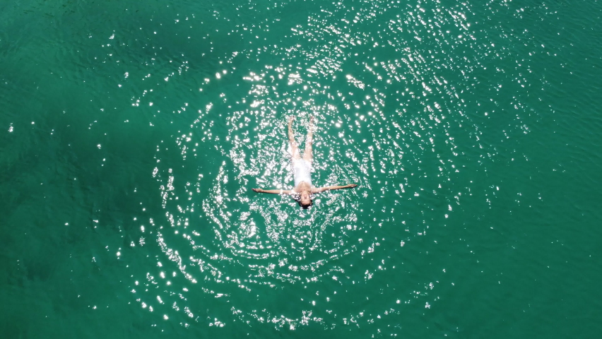 Aerial view of swimming woman in Blue Lagoon. Summer seascape with girl, clear azure water. Transparent water. Top view from flying drone. Travel | Shutterstock HD Video #1085703254
