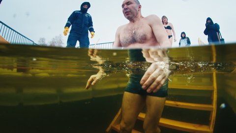 IZHEVSK, RUSSIA - JANUARY 19, 2022: Russian Orthodox believer swims in the icy water to celebrate the Epiphany